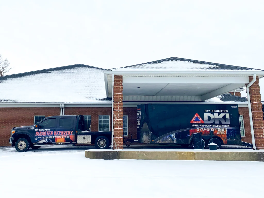 Image of SKY Restoration fleet vehicles parked under an overhang in the snow.